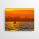 Das Bild zeigt ein Akustikbild vor einer weißen Wand. Zu sehen ist ein See, auf welchem ein Segelboot ruht, eingetaucht in das kräftige Orange des Sonnenuntergangs. Bei so einem traumhaften Anblick auf dem Boot unterwegs zu sein - Was für ein Segelglück!